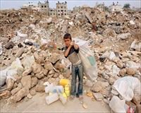 Palestinian boy standing in the midst of a giant pile of trash in Gaza.