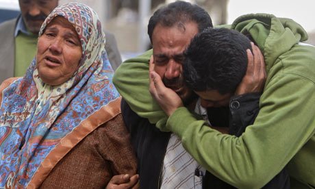 Umm Ahmed Abu Rahmeh, left, and her two sons, react as the body of her son Bassem arrives at a hospital.