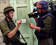 Photo of an Israeli soldier checking a cameraman’s press card.