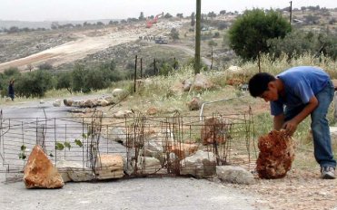 Non-violent resistance takes many forms. Here, a Palestinian boy builds a roadblock with rocks and wire hoping to deter the Israeli army from invading his village during the night.