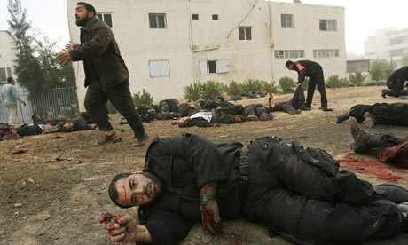A wounded Palestinian policeman gestures while lying on the ground outside Hamas police headquarters following an Israeli air strike in Gaza City.